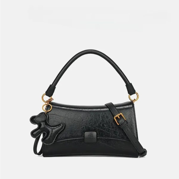 Black small purse with dog charm featuring a top handle and adjustable shoulder strap