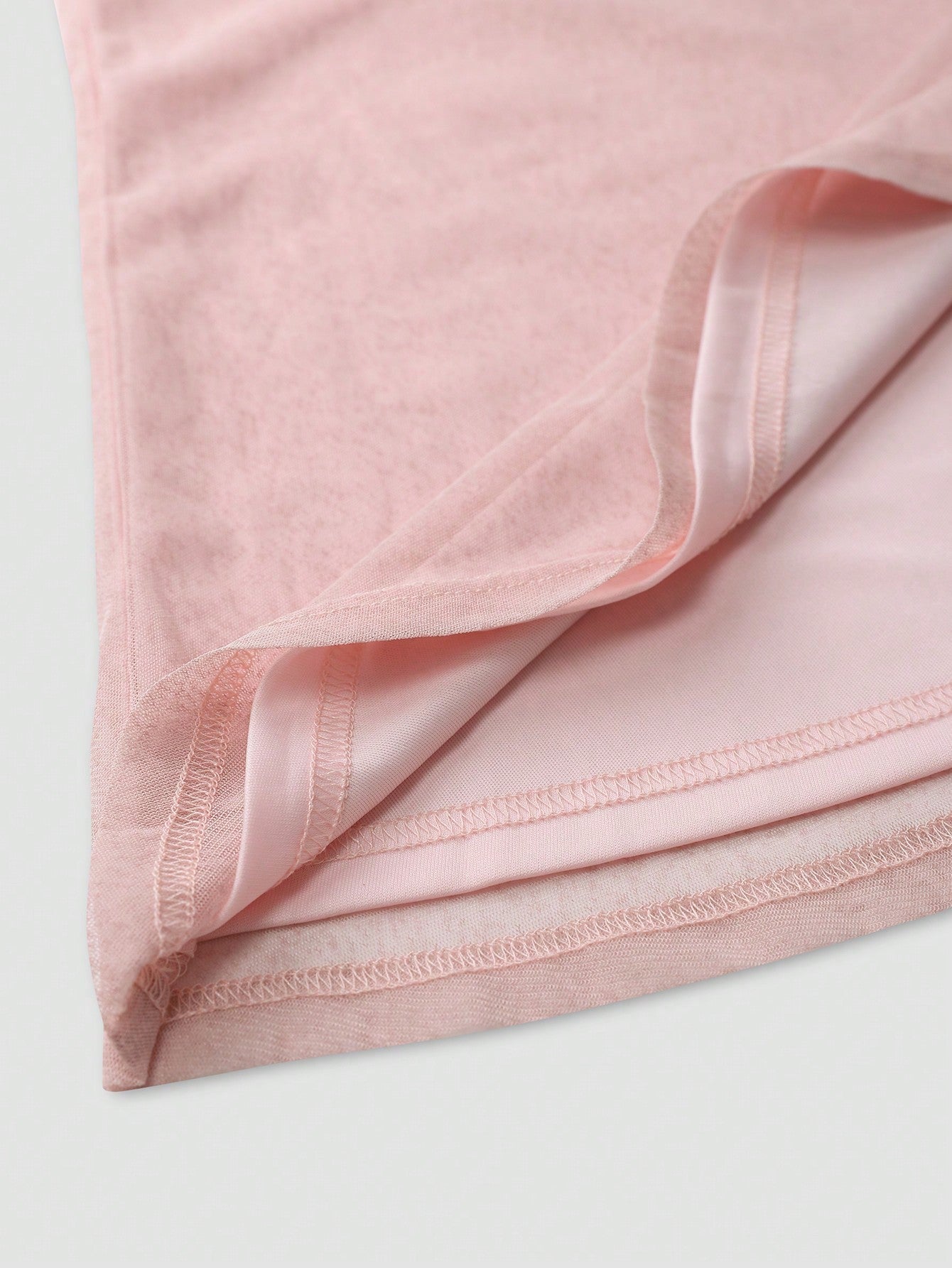 Close-up of soft pink fabric detail of an elegant wedding guest dress showing stitching and texture