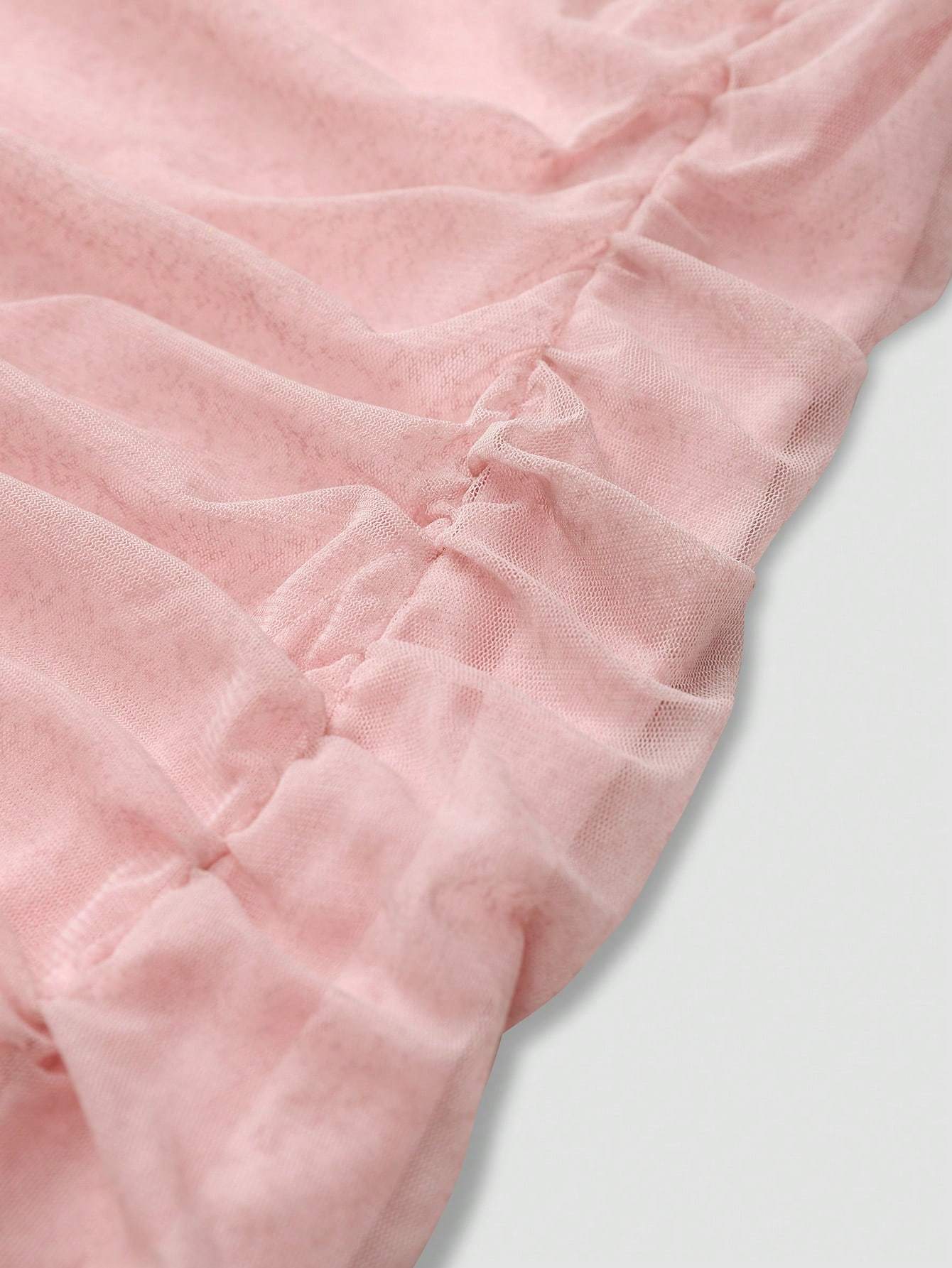Close-up detail of soft pink fabric with ruching on an elegant wedding guest dress