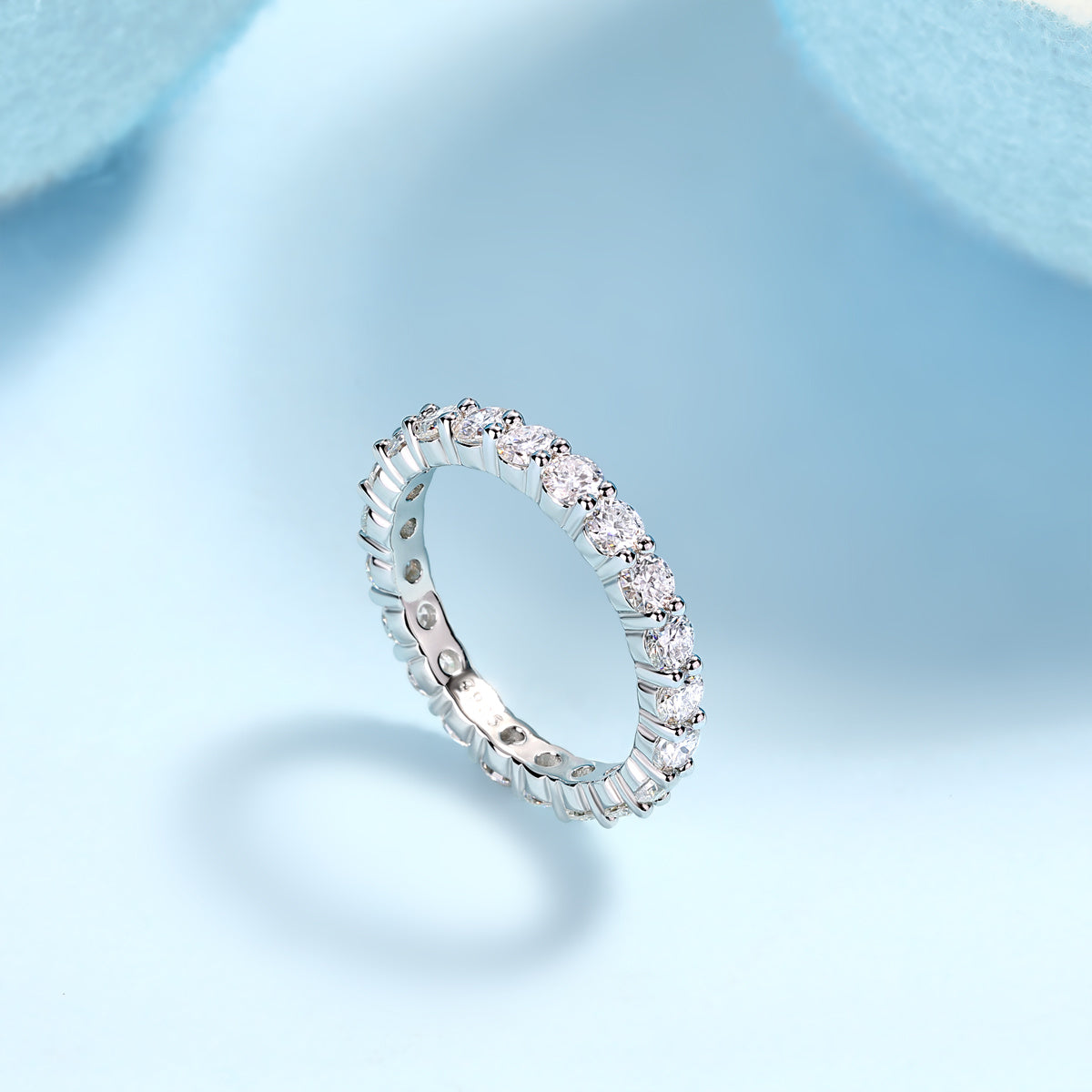 925 sterling silver moissanite ring with sparkling stones all around on light blue background