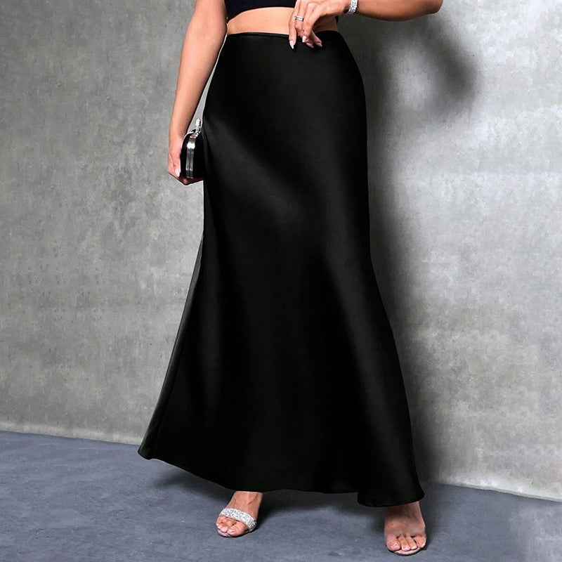 Black elegant satin midi skirt worn with silver open-toe heels and a black crop top