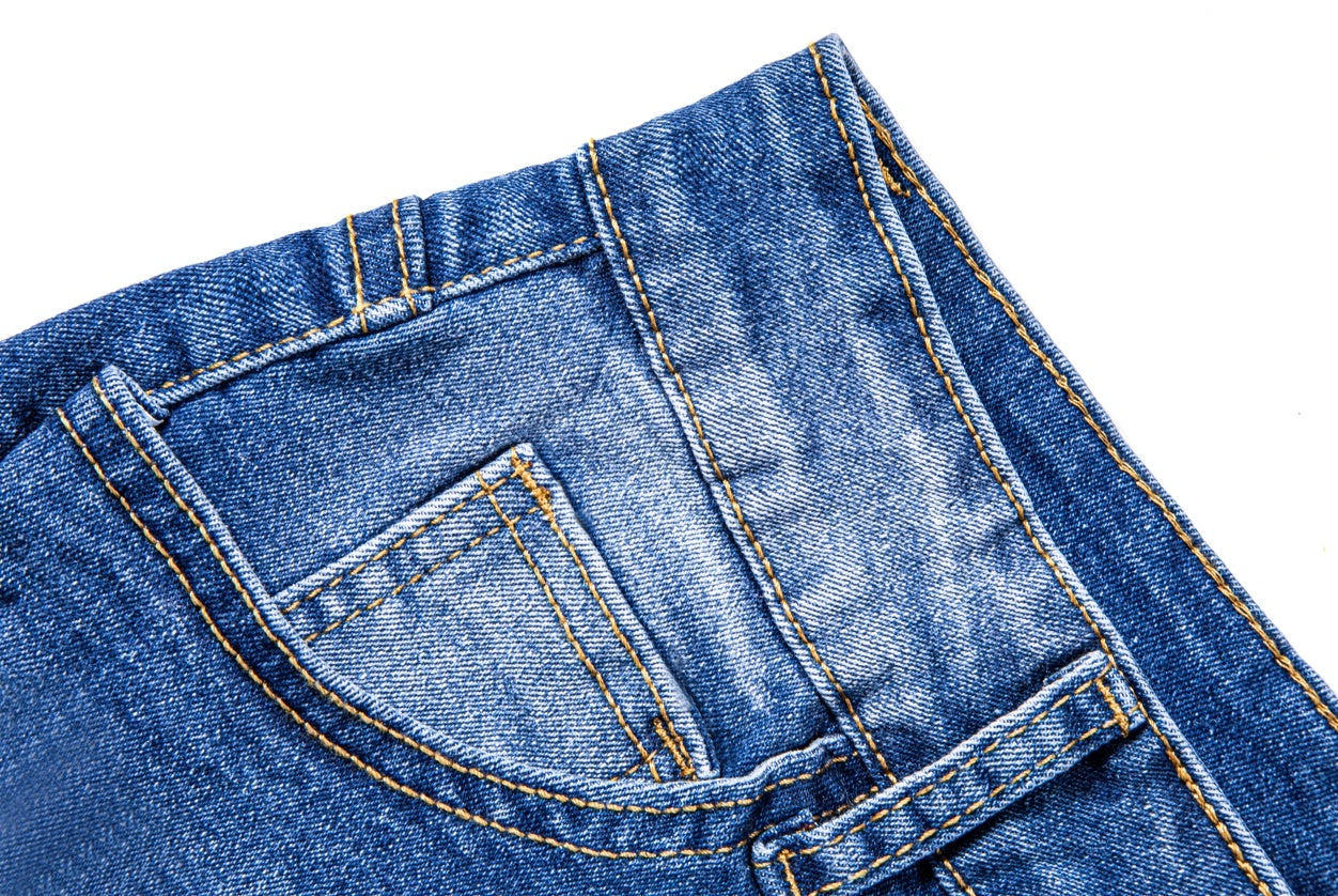 Close-up of blue women's ripped denim shorts pocket stitching and fabric texture