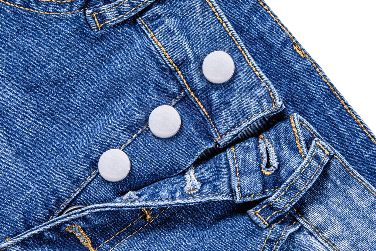 Close-up of blue women's ripped denim shorts with white buttons and detailed stitching