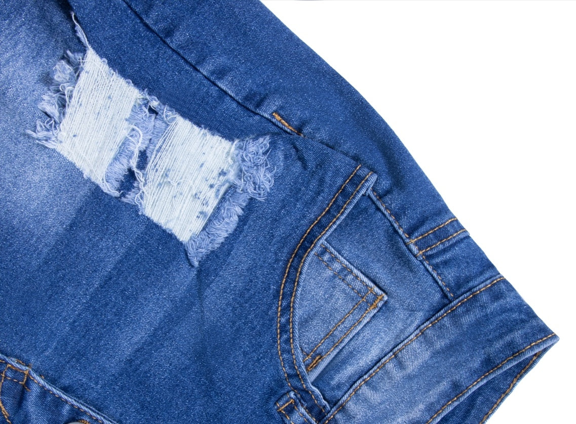 Close-up of blue women's ripped denim shorts showing frayed tear and front pocket details