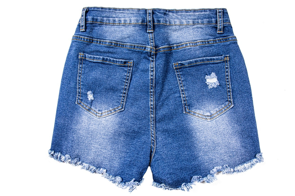 Back view of women's ripped denim shorts in blue with frayed edges and distressed pockets