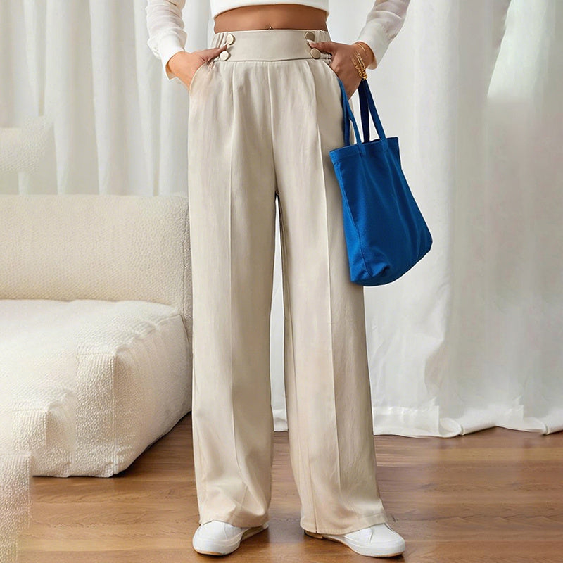 Beige women's wide leg business trousers with high waist and button details styled with white sneakers and blue tote bag