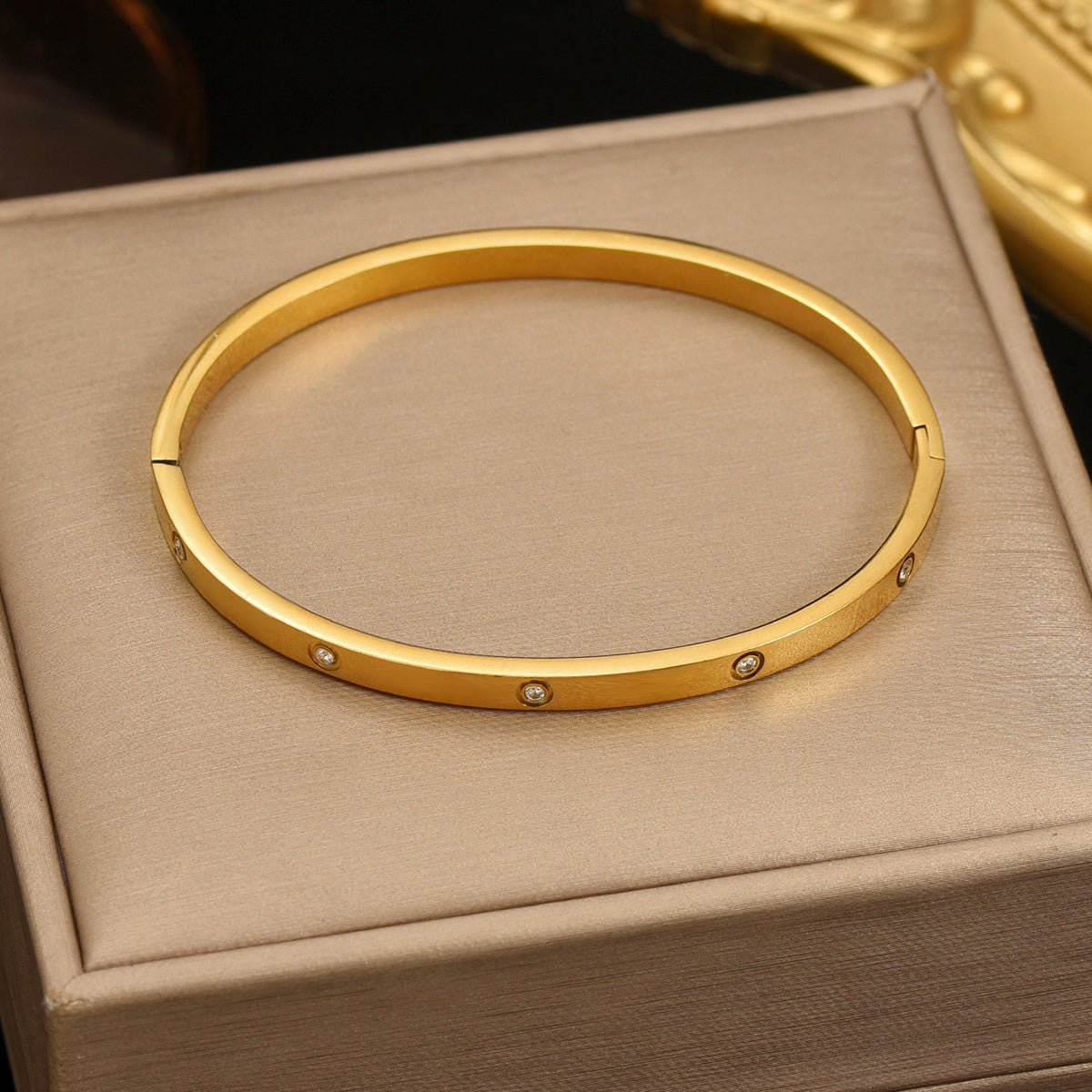 LUNIVA CARE USA 18K gold plated bracelet for women with small embedded stones on a beige cushion