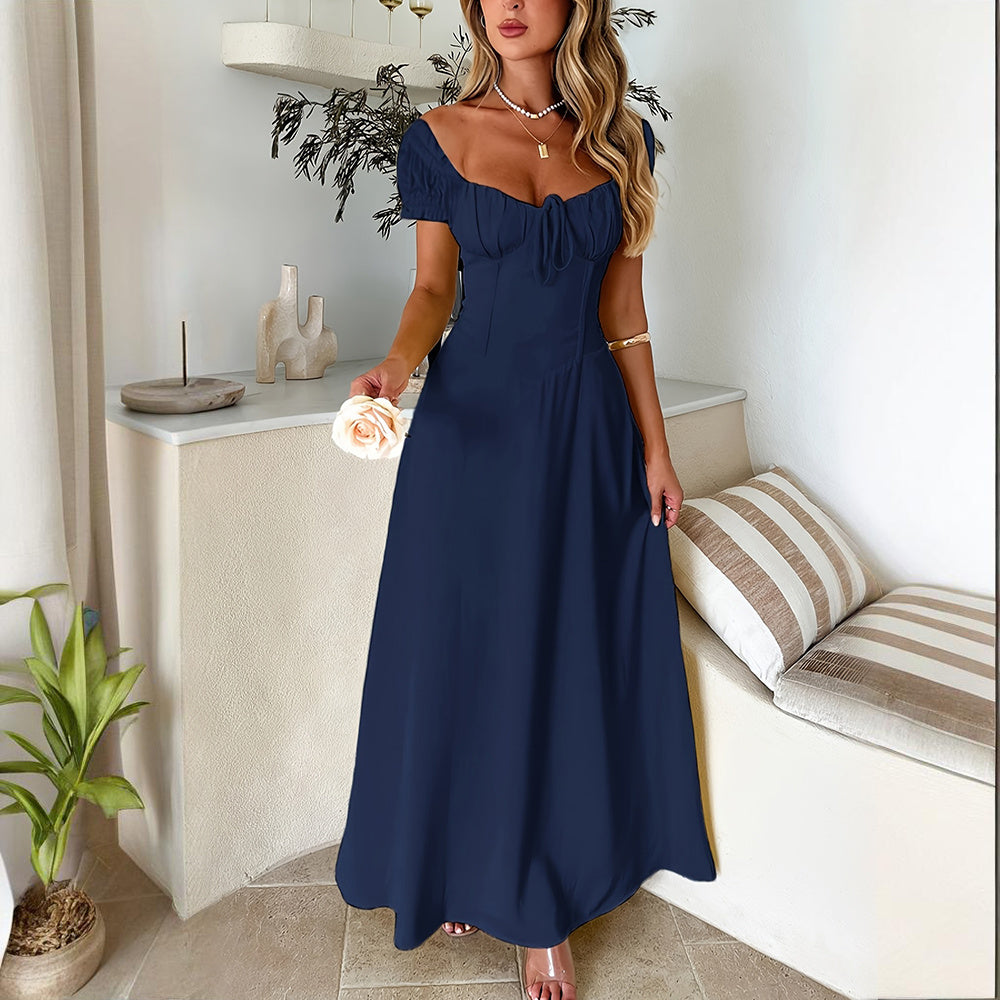 Woman wearing navy blue bohemian backless maxi dress with short puff sleeves standing indoors