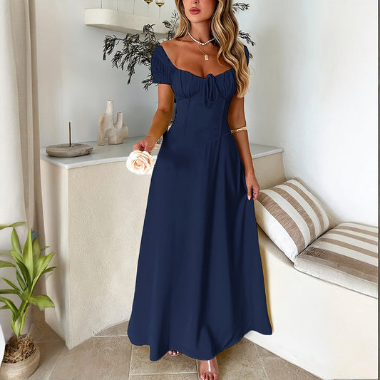Woman wearing navy blue bohemian backless maxi dress with short puff sleeves standing indoors