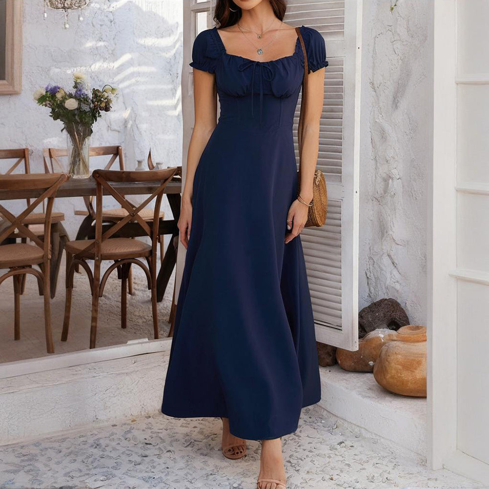 Woman wearing navy blue bohemian backless maxi dress with short sleeves in a rustic indoor setting