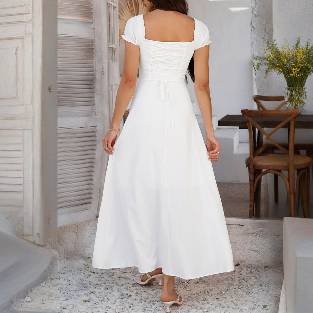Woman wearing a white bohemian backless maxi dress with puff sleeves and lace-up back