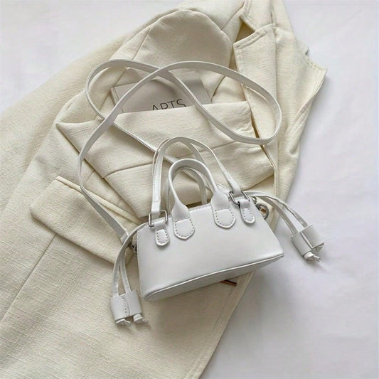Elegant top handle clutch bag in white with long strap on beige textured fabric background