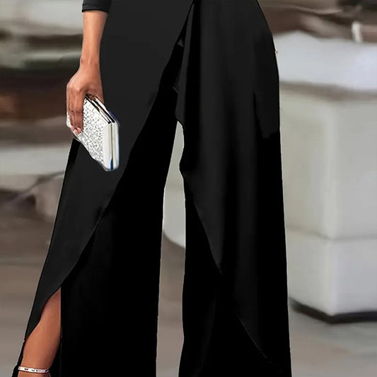 Black formal party jumpsuit with pants slit and silver clutch held by model