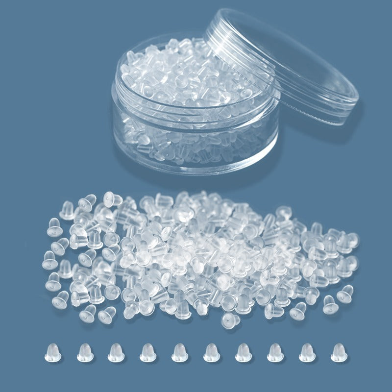 Clear silicone earring backs from LUNIVA CARE USA in a small open container and scattered on blue surface