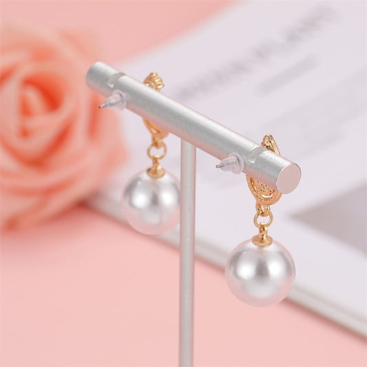 LUNIVA CARE USA pearl earrings with gold accents and clear silicone earring backs displayed on stand