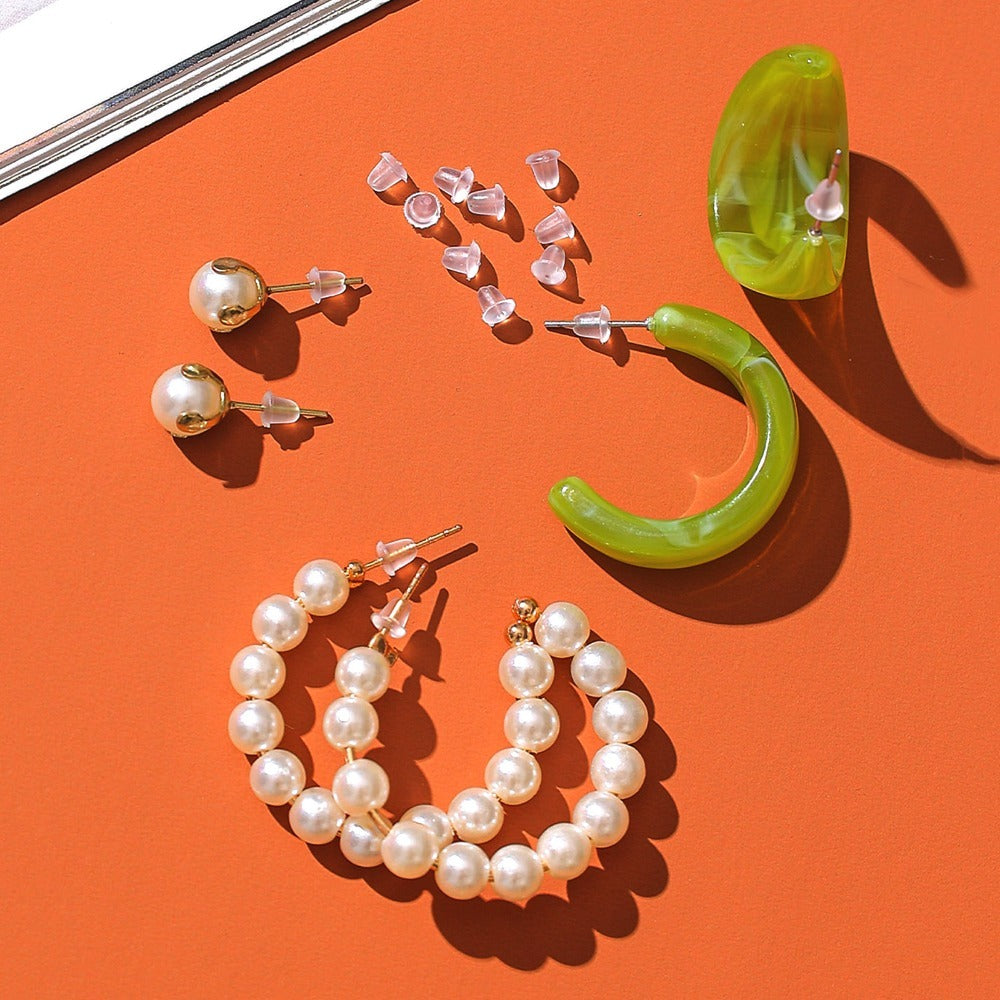 LUNIVA CARE USA silicone earring backs with pearl and green hoop earrings on orange background