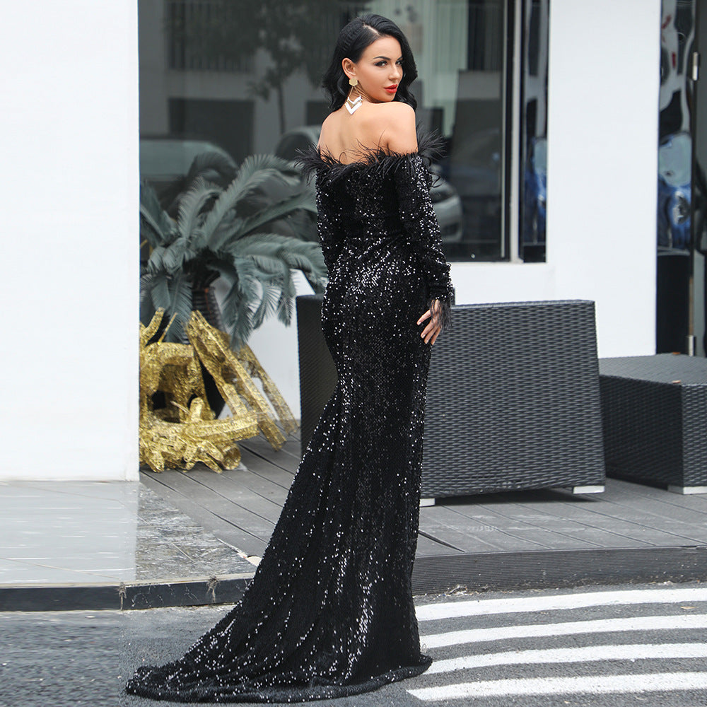 Woman wearing a black off shoulder sequin maxi dress with long sleeves and feather details standing outdoors