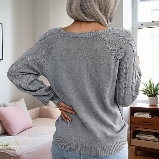 Woman wearing gray solid color pullover sweater women with cable knit sleeves standing by window
