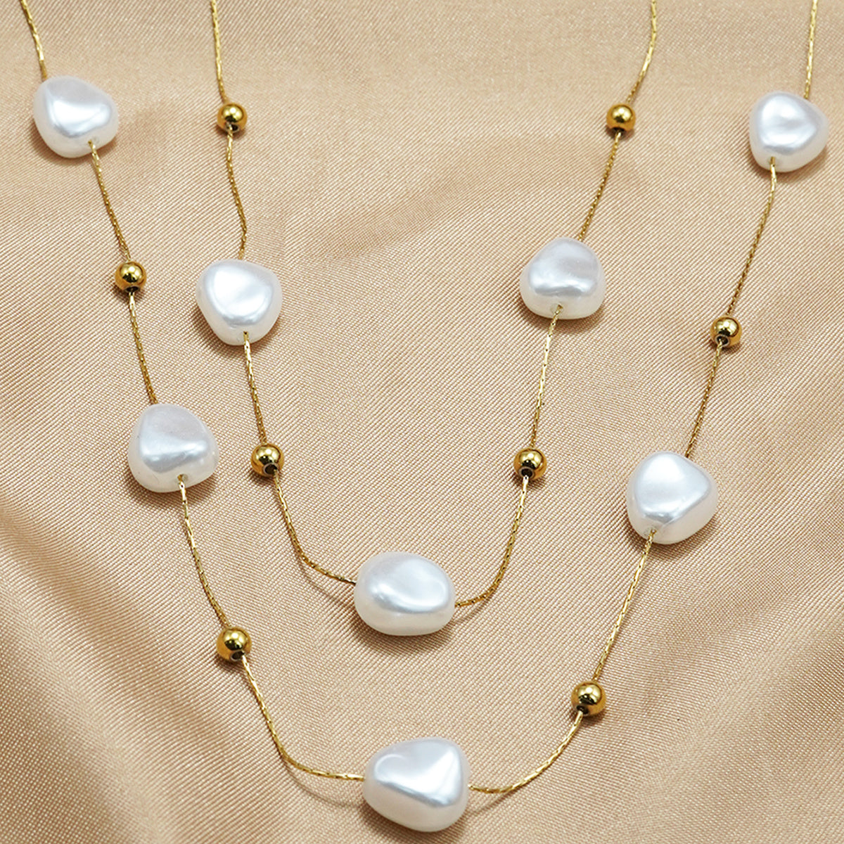 LUNIVA CARE USA 18K gold plated pearl necklace with irregular pearls and gold beads on satin background