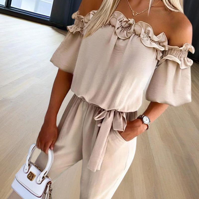 Woman wearing elegant off-shoulder jumpsuit for women in beige with ruffle detail and tie waist