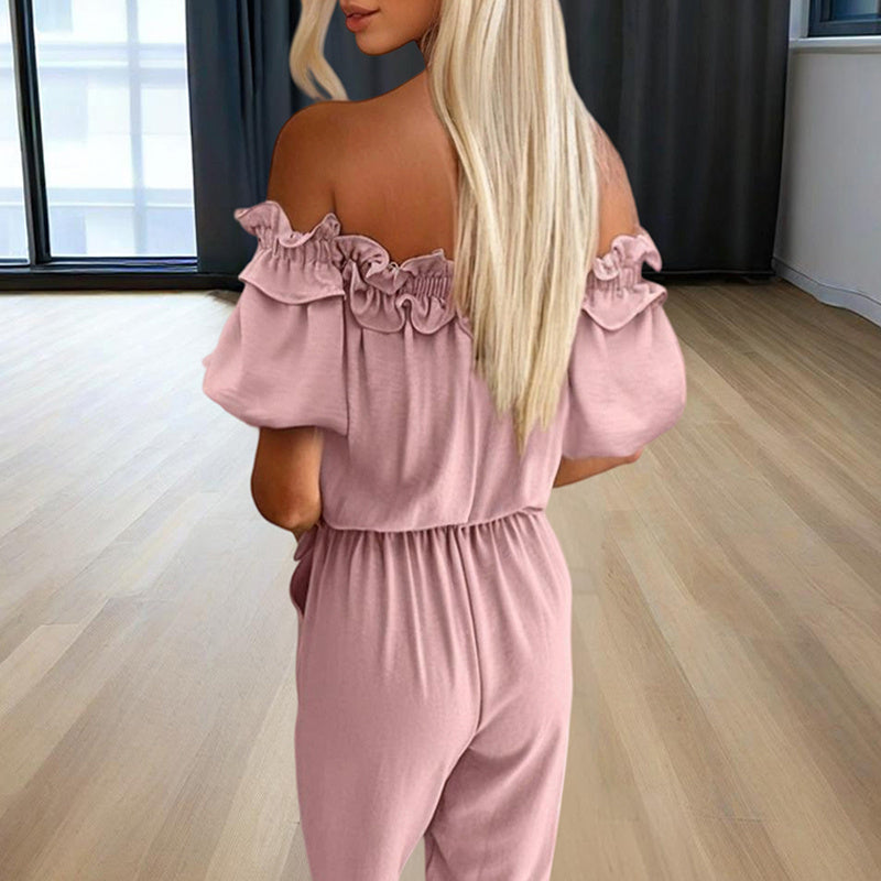 Back view of a woman wearing an elegant off-shoulder jumpsuit for women in soft pink indoors