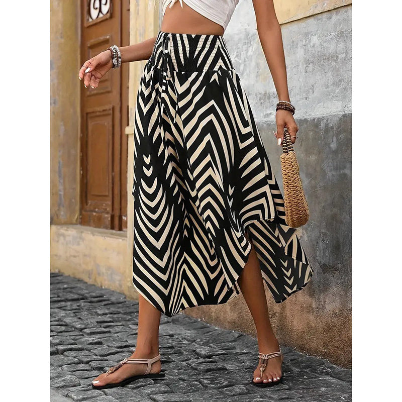 Woman wearing black and beige patterned high waist floral midi skirt with side slit and sandals