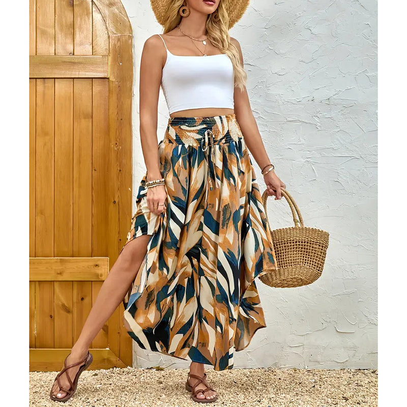 Woman wearing a high waist floral midi skirt with abstract leaf print and white crop top holding a woven bag