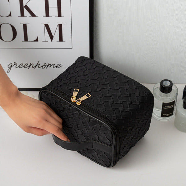 LUNIVA CARE USA black waterproof cosmetic bag with compartments and gold zippers being held on a white surface