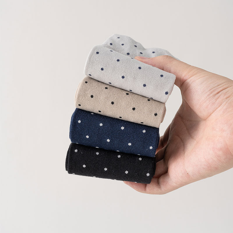 Hand holding a stack of women's cute crew socks in gray, beige, navy, and black with polka dot patterns