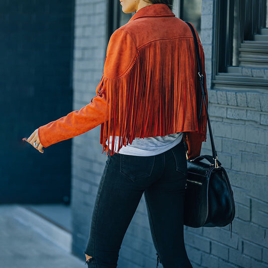 Back view of a woman wearing an orange women's faux suede fringe jacket with black jeans and black handbag