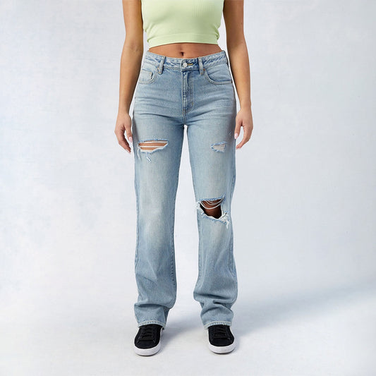 Light blue distressed women's high-waist wide leg jeans styled with black sneakers and crop top
