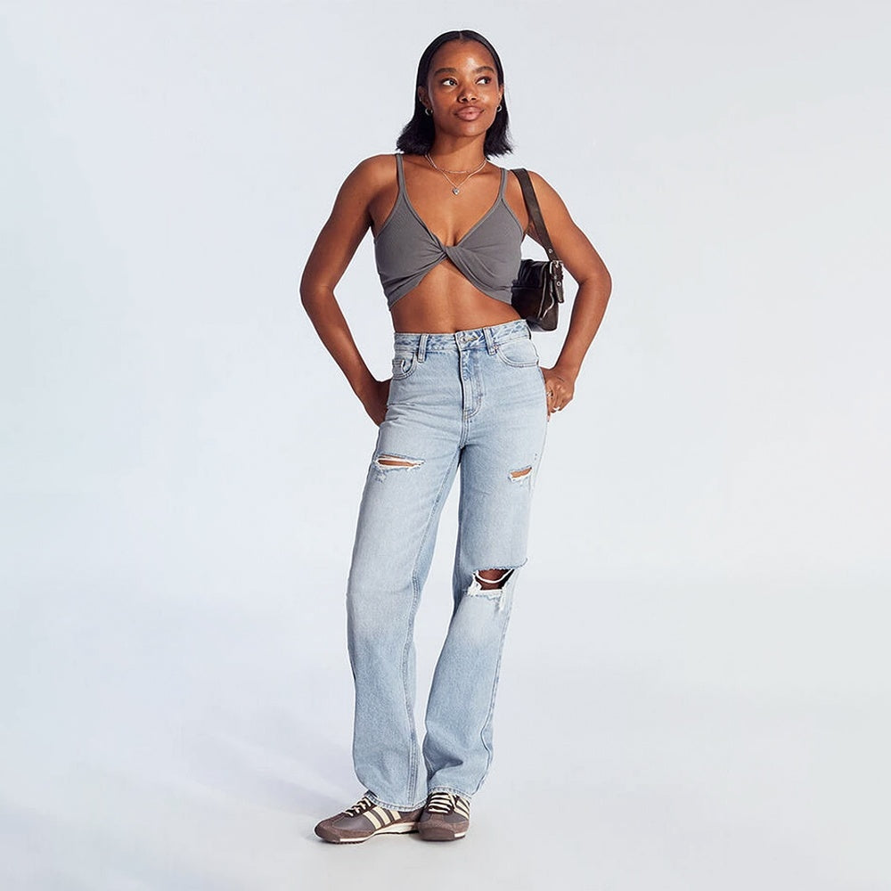 Woman wearing women's high-waist wide leg jeans with a gray crop top and sneakers