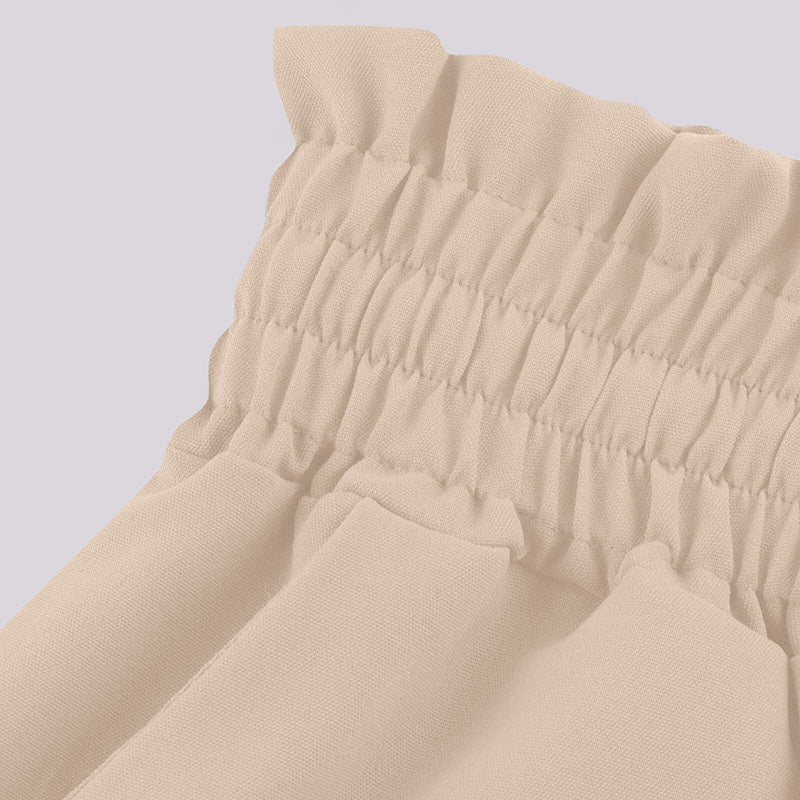 Close up of beige elastic waistband on women's high waist wide leg pants showing gathered fabric detail