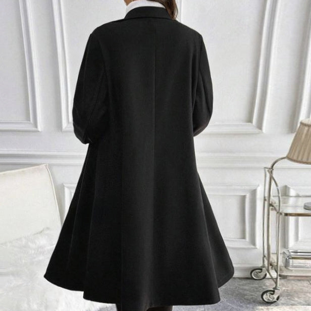 Back view of women's long sleeve knit jacket in black worn indoors with elegant design and flowing hem