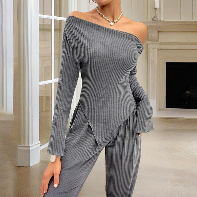 Gray ribbed women's off-shoulder lounge set with long sleeves and matching pants in a cozy indoor setting