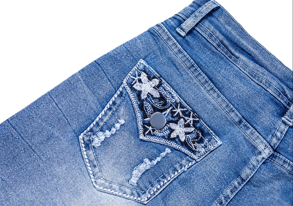 Close-up of womens ripped jean shorts pocket with floral embroidery and distressed details