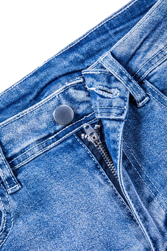Close-up of womens ripped jean shorts blue denim with zipper and button detail