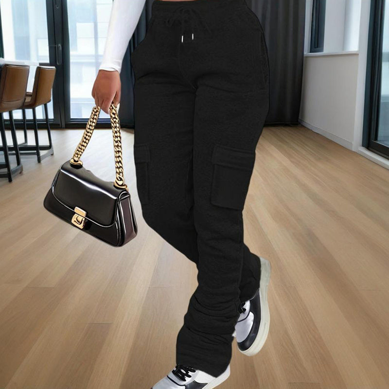 Woman wearing black women's straight leg pants with cargo pockets and white sneakers holding a black handbag