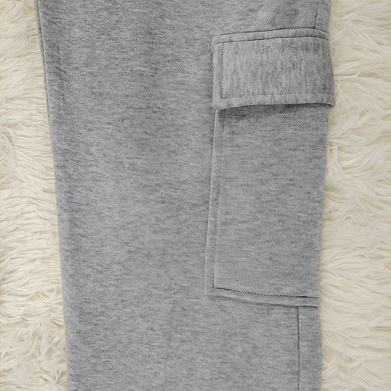 Close-up of gray fabric pocket detail on women's straight leg pants laid on beige textured surface