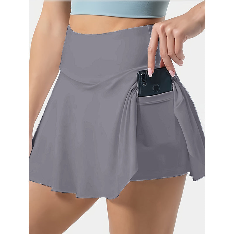 Gray women's tennis skirt with pockets holding a black smartphone and high waistband